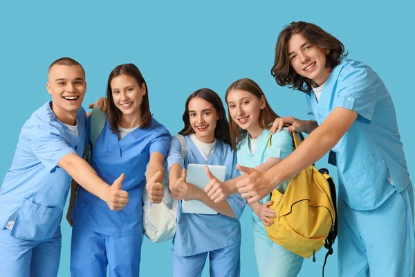 Group of medical students showing thumbs-up on blue background