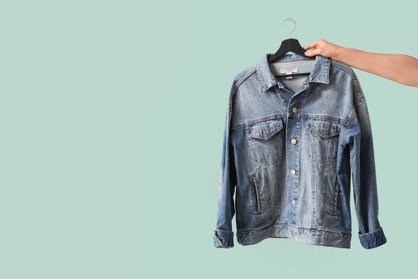 Female hand with denim jacket on green background