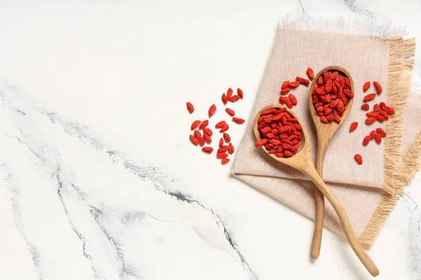 Beyaz arka planda kırmızı kurutulmuş goji üzümlü tahta kaşıklar.