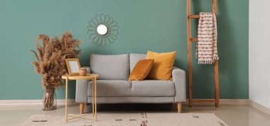 Gri kanepesi, masası ve merdiven rafı olan şık bir oturma odası.