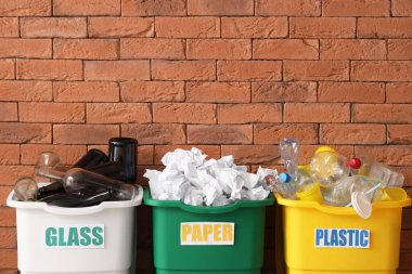 Kahverengi tuğla duvarlı farklı geri dönüşüm kutuları. Geri dönüşüm kavramı