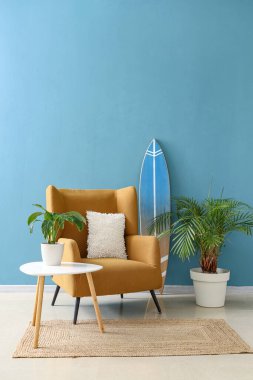 Oturma odasının içinde sörf tahtası, koltuk ve masa var.