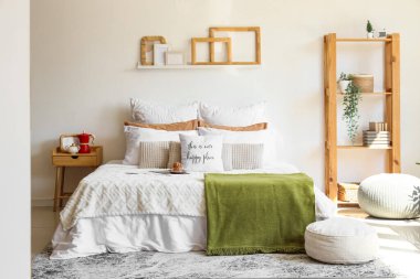 Muffin, komodin, raflar ve yatak odasının içi puf dolu büyük, rahat bir yatak.