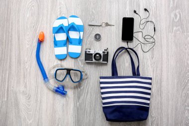 Hafif ahşap zemin üzerinde boş cep telefonu olan gezgin plaj aksesuarları.