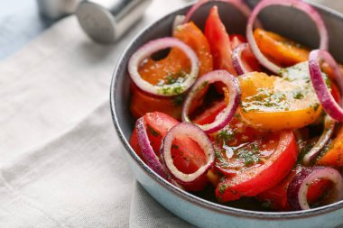 Bir kase taze domates salatası, peçetede kırmızı soğan, yakın plan.