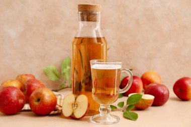 Bej arka planda meyveli taze elma şarabı şişesi ve cam bardak.