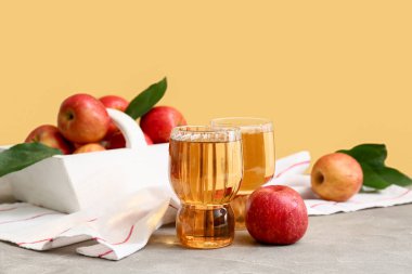 Gri masadaki meyveli taze elma suyu ve sepeti.