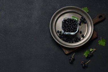 Siyah arka planda taze siyah üzümlü cam kase ve tabak.