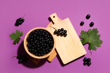 Mor arka planda taze siyah üzümlü ahşap kase.