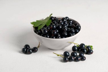 Beyaz arka planda taze siyah üzümlü kase, yakın plan.