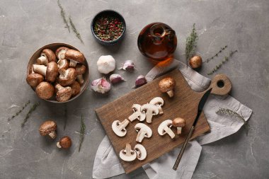 Ahşap tahta ve kasede gri arka planda taze çiğ mantar var.