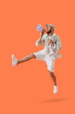 Turuncu arka planda megafonla atlayan yakışıklı genç adam.