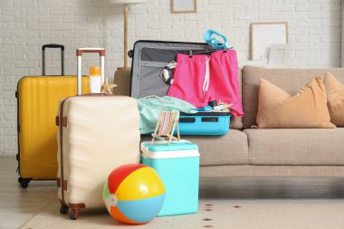 Oturma odasında erkek mayosu ve plaj aksesuarları olan bavullar.