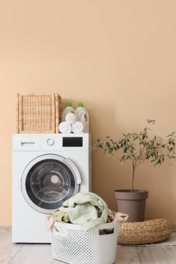 Çamaşır sepetli ve çamaşır makineli çamaşır odasının içi.