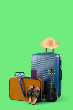 Pasaportlu bavullar ve yeşil arka planda aksesuarlar. Seyahat kavramı
