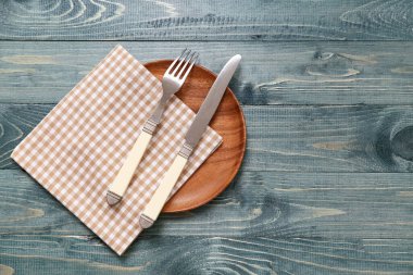 Gri ahşap arka planda tabak, çatal bıçak ve peçete.