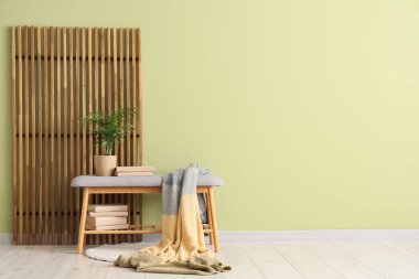 Rahat battaniyeli gri bank, kitaplar ve yeşil duvarın yanındaki bitki örtüsü.