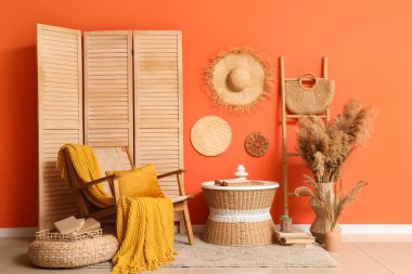 Oturma odasının içinde rahat koltuk, masa ve katlanabilir ekran.