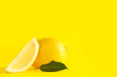 Taze limonlar ve sarı arka planda yeşil yaprak, yakın plan.