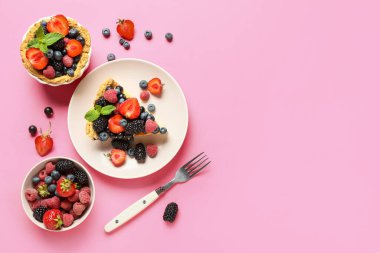 Lezzetli böğürtlenli pasta ve pembe arka planda malzemeler.