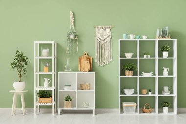 Mutfağın içinde temiz bulaşık takımları ve ev bitkileri olan raflar.