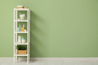 Mutfağın içinde temiz bulaşık takımları ve ev bitkileri olan raf ünitesi.