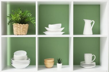 Mutfakta temiz bulaşık takımları ve ev bitkileri olan raf ünitesi, yakın plan.