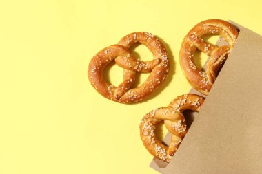 Sarı arka planda lezzetli krakerlerin olduğu kağıt torba, yakın plan.