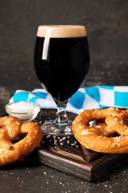 Bir bardak soğuk bira ve siyah grunge arka planda lezzetli krakerler, yakın plan.