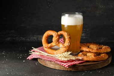 Bir bardak soğuk bira ve siyah grunge arka planda lezzetli krakerler, yakın plan.