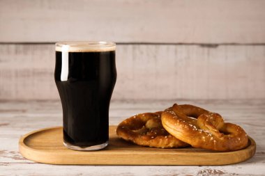 Bir bardak soğuk bira ve ahşap arka planda lezzetli krakerler, yakın plan.