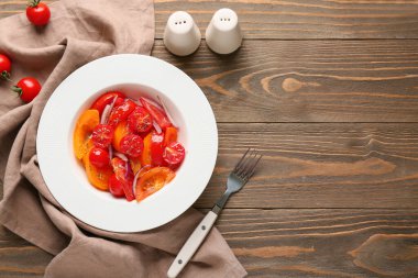 Ahşap zemin üzerinde kırmızı soğan olan taze domates salatası.