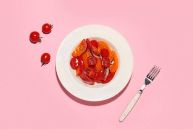 Pembe arka planda kırmızı soğanlı taze domates salatası.