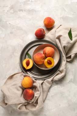 Gri arka planda tatlı olgun şeftalilerle dolu bir kase.