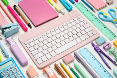 Farklı okul gereçleri ve beyaz arkaplanda bilgisayar klavyesi olan kompozisyon, yakın plan