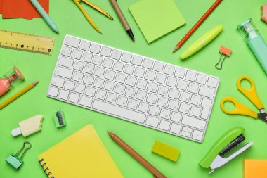 Yeşil arka planda bilgisayar klavyeli okul gereçleri, yakın plan
