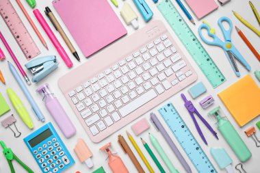 Farklı okul gereçleri ve beyaz arkaplanda bilgisayar klavyesi olan kompozisyon, yakın plan