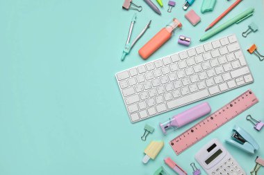 Mavi arka planda bilgisayar klavyesi olan okul malzemeleri.