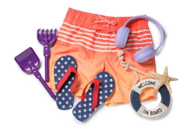 Beyaz arka planda plaj aksesuarları olan çocuk yüzme şortu.