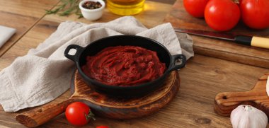 Kızartma tavasında domates ezmesi ve mutfak masasındaki malzemeler.