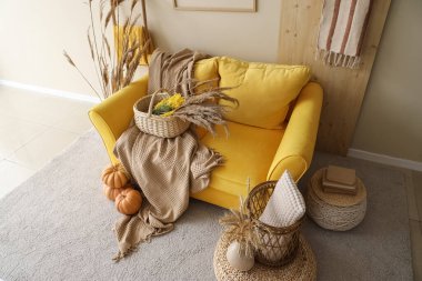 Sarı kanepe, balkabakları, otlar ve ekoseler sonbaharda oturma odasının içinde.