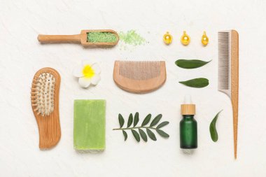 Saç fırçası, tarak, vitamin kapsülleri ve beyaz grunge arka planda bir şişe kozmetik ürünü içeren kompozisyon, yakın plan