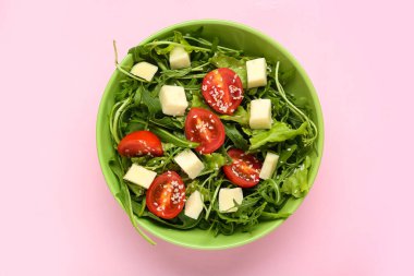 Pembe arka planda lezzetli roka salatası, yakın plan.