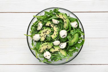 Beyaz ahşap arka planda lezzetli roka salatası, yakın plan.