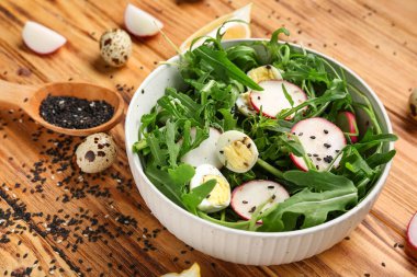 Tahta arka planda sağlıklı roka salatası, yakın plan.