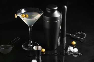 Farklı barmen aletleri, kokteylli bardak ve siyah arka planda malzemeler, yakın plan.
