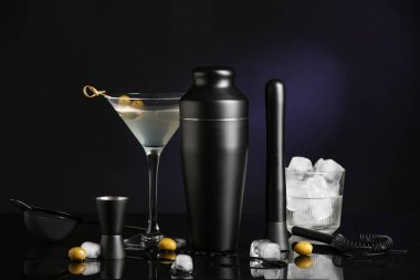 Farklı barmen aletleri, kokteyl bardakları ve siyah arka plan malzemeleri.