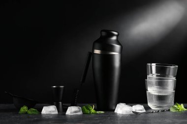 Barmen aletleri, boş bardaklar ve kokteyl malzemeleri siyah duvarın yanındaki masada.