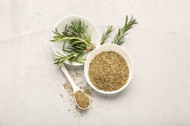 Kurumuş biberiyeli kaseler ve bej rengi grunge arka planda taze yeşil dallar, yakın plan.