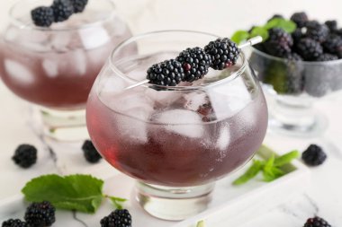 Lezzetli böğürtlenli limonata ve beyaz duvarın yanındaki mermer masada malzemeler.